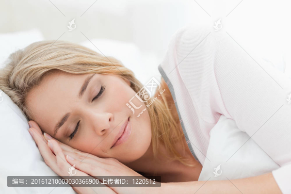 睡在床上的女人；雙手枕在枕頭上，被一床被子蓋住。