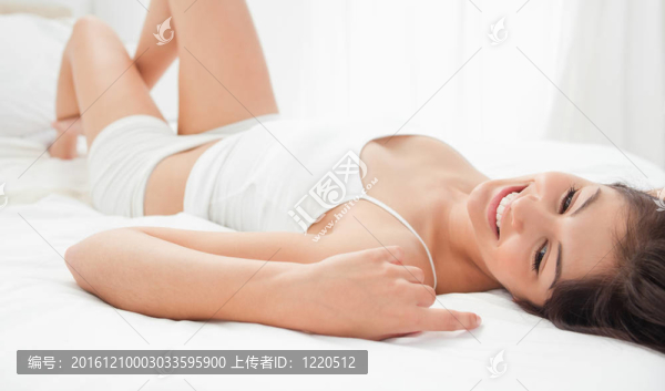 一個(gè)女人躺在床上，膝蓋微微抬起，微笑著。