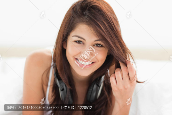 一個(gè)女人微笑著躺著，向前看，手里拿著一些頭發(fā)。
