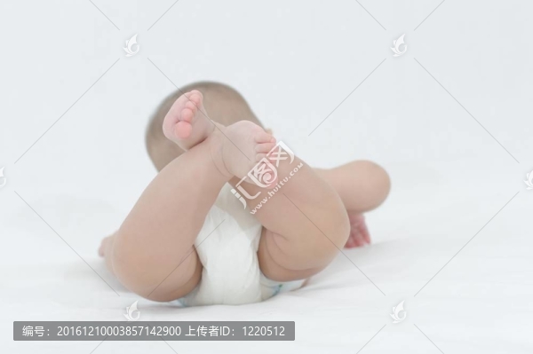 快樂(lè)的微笑的孩子在白色的床上玩耍；展示她的小腳