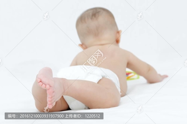 快樂的微笑的孩子在白色的床上玩耍；展示她的小腳