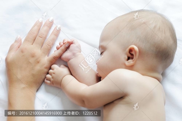 嬰兒睡覺靠近她的母親，握著她的手指