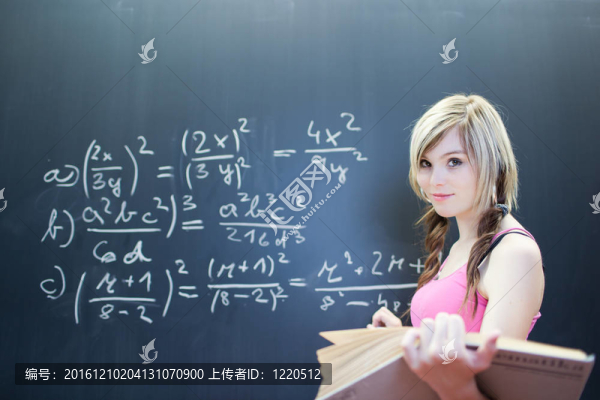 年輕漂亮的大學(xué)生寫在黑板上/黑板上數(shù)學(xué)課期間（淺景深；顏色色調(diào)的圖像）