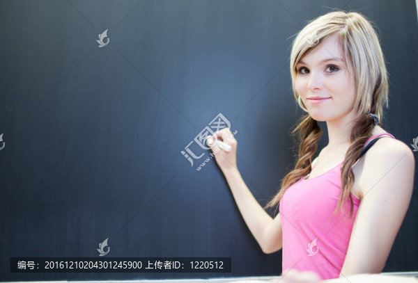 年輕漂亮的大學(xué)生寫(xiě)在黑板上/黑板上數(shù)學(xué)課期間（淺景深；顏色色調(diào)的圖像）