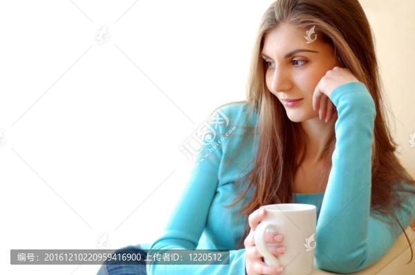 年輕漂亮的女人在家喝茶。白色背景與文字空間。