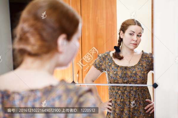 年輕白人女性的肖像在穿著鏡子和看著自己在家里