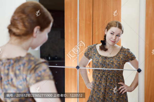 年輕白人女性的肖像在穿著鏡子和看著自己在家里