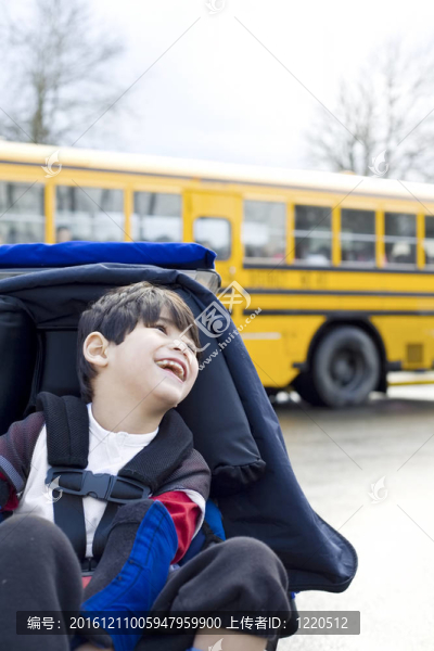 殘疾的五歲男孩坐在輪椅上的校車；