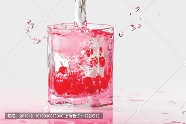 杯水；冰和紅色的越橘在粉紅色的光閃