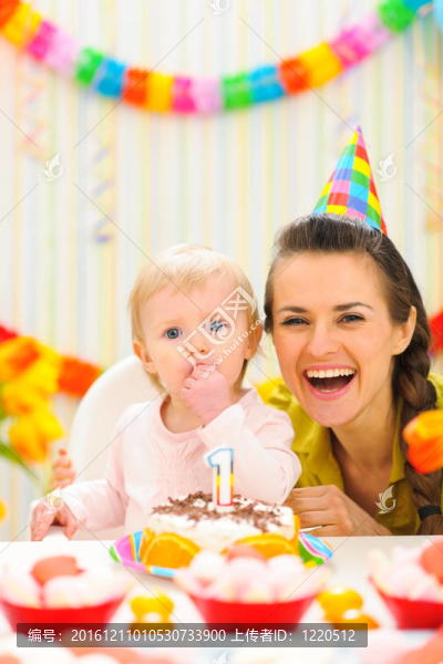 母親與嬰兒享受第一個生日蛋糕肖像