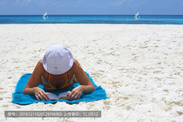 年輕婦女正在海灘上看這本書