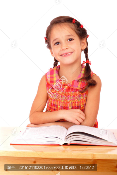 微笑的小女孩在書(shū)桌上看書(shū)；在白色上孤立