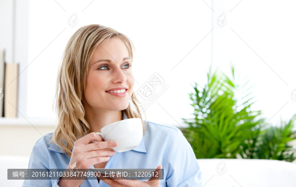 迷人的女商人拿著杯子坐在沙發(fā)上