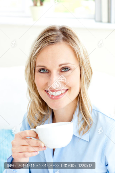 迷人的女商人拿著杯子坐在沙發(fā)上