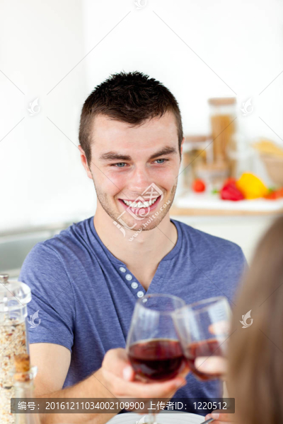 英俊的年輕男子和他的女朋友吃晚飯喝了酒在家里的廚房