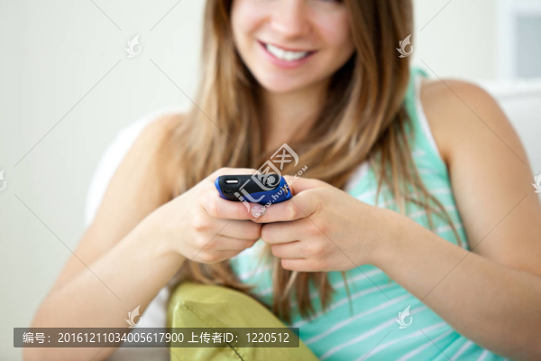 一個漂亮的年輕女人在客廳的沙發(fā)上用手機發(fā)短信