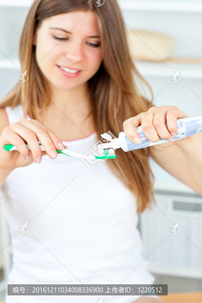 美麗的女人用牙刷和牙膏在浴室在家里