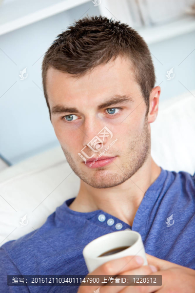 迷人的白人男子在家里的客廳里拿著一杯咖啡
