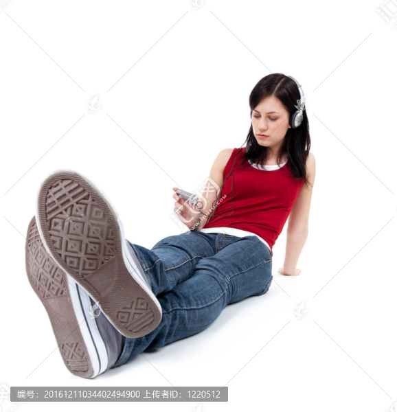 在MP3播放器的耳機(jī)坐在地板上的年輕女子