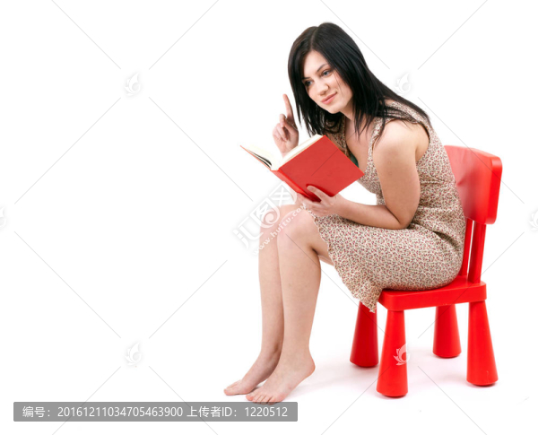 坐在紅色的；孩子的椅子年輕女子讀書(shū)