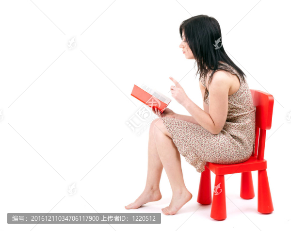 坐在紅色的；孩子的椅子年輕女子讀書
