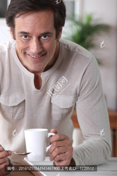 男人笑著喝杯茶。