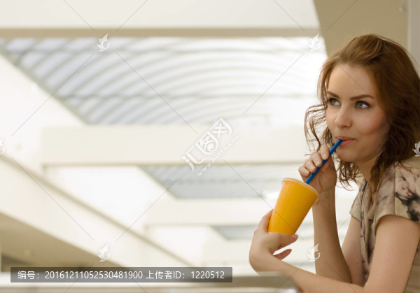 一個美麗的年輕女子在購物中心的一杯果汁肖像