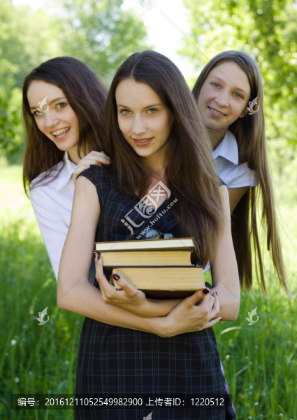 三快樂的學生女孩在公園里看書