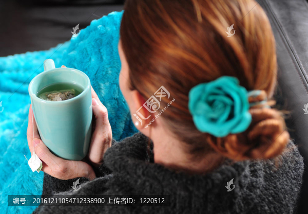 沙發(fā)上的女人用毯子和一杯茶