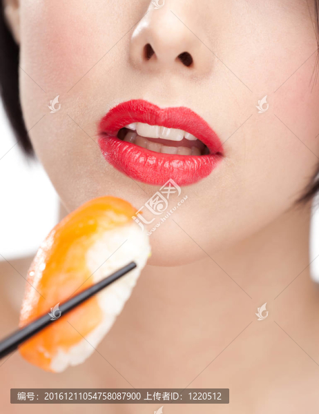 漂亮的女人拿著壽司用筷子；特寫