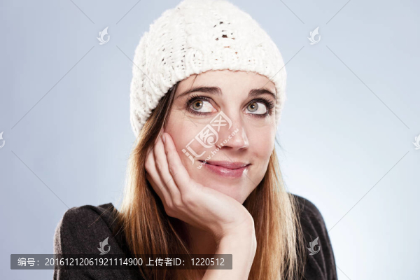 戴著冬帽的女人仰望著淺藍(lán)色的背景