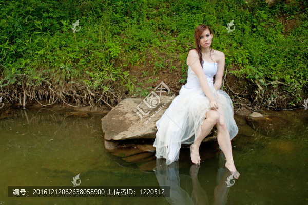 濕漉漉的女人坐在水上的巖石上