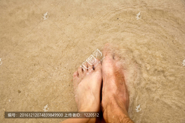 一個(gè)人的腳在細(xì)砂包圍的海水