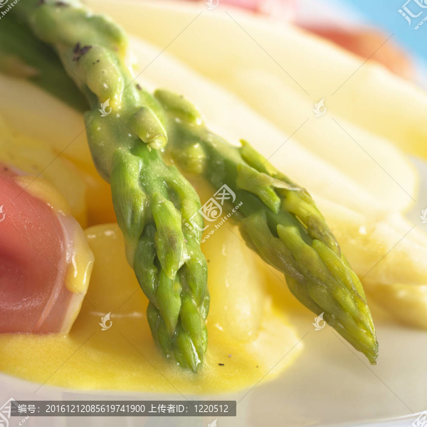 綠色蘆筍煮在一邊上火腿片荷蘭醬土豆塊（選擇性聚焦；對蘆筍頭焦點）