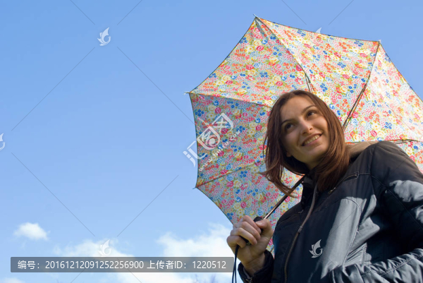 畫面中一位年輕快樂微笑的女孩站在雨中帶著傘