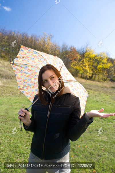 畫面中一位年輕快樂微笑的女孩站在雨中帶著傘