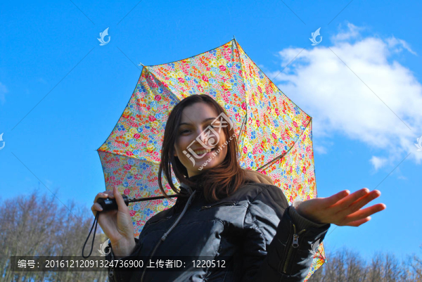畫面中一位年輕快樂微笑的女孩站在雨中帶著傘