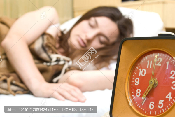 年輕的女人正在一個紅色的鬧鐘