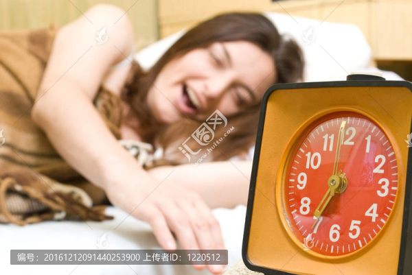 年輕的女人正在一個(gè)紅色的鬧鐘