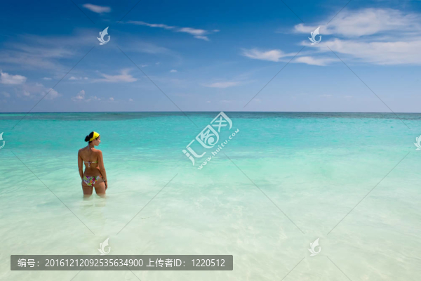 曬黑的女孩站在明亮的藍(lán)色海洋