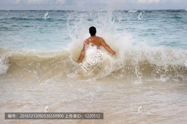 皮膚黝黑的男子在海浪的藍(lán)色海洋跳躍
