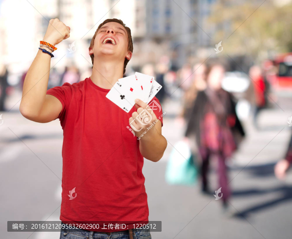 年輕人在擁擠的地方做勝利者的姿勢(shì)打撲克的肖像