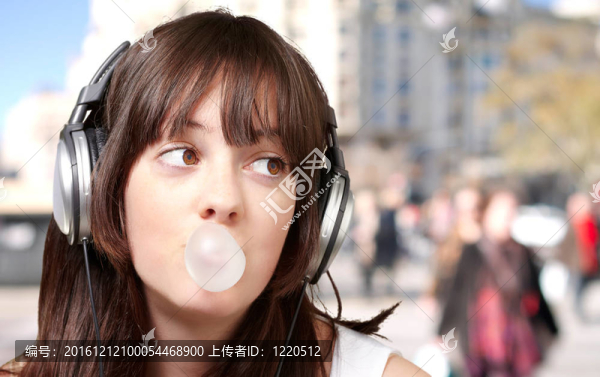 年輕女子在擁擠的街道上用泡泡糖聽音樂的肖像