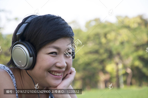 美麗的亞洲女人在公園聽音樂