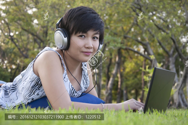 美麗的亞洲女人在公園聽音樂