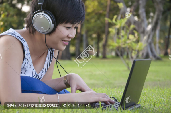 美麗的亞洲女人在公園聽音樂