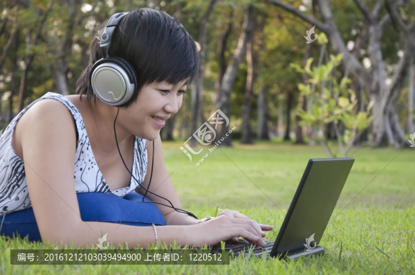 美麗的亞洲女人在公園聽音樂