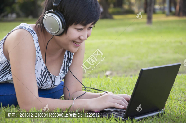 美麗的亞洲女人在公園聽音樂