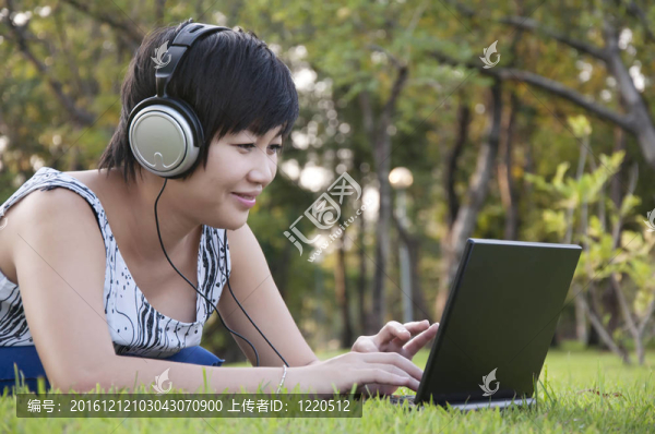 美麗的亞洲女人在公園聽音樂