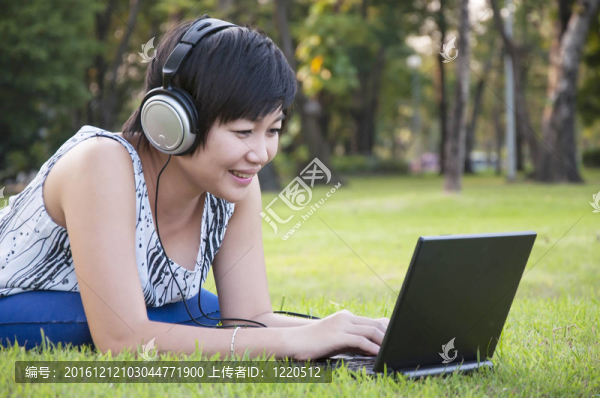 美麗的亞洲女人在公園聽音樂